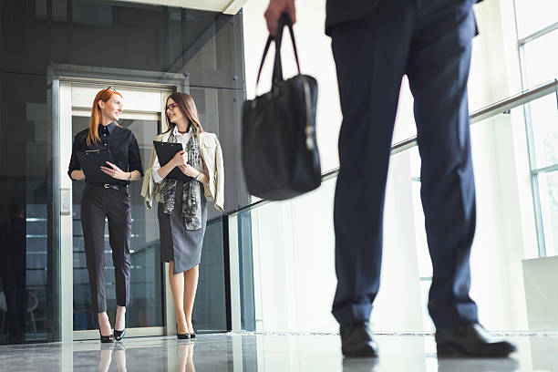 Two businesswoman exiting the elevator and walking stock photo