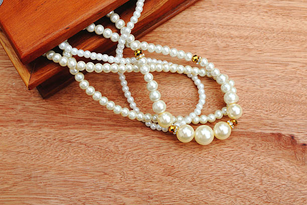 istock pearl necklace pouring from wooden box 525804420