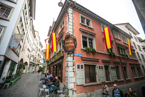 Zurich, Switzerland  - May 1, 2014: Zurich street with cafe and tourists walking in the city