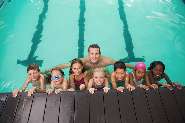istock Cute swimming class in pool with coach 525805347