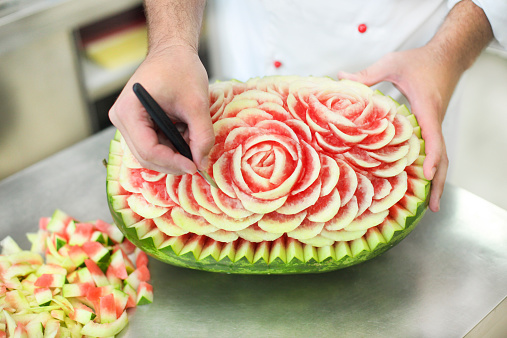 Chef carving a watermelon in a kitchen