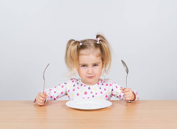 istock Little girl holding fork and spoon with 525807136