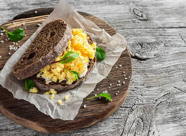 Scramble egg sandwich on rustic wooden background. Healthy breakfast or snack