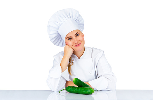 Chef woman. Isolated over white background by the table with cucmber