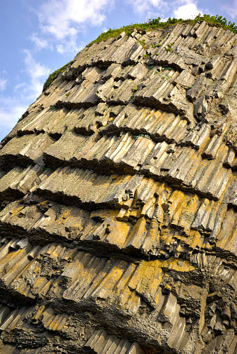 Wall natural stone grass. Volcanic rocky formation. basalt lava column wall, giants causeway, Stolbchaty Cape; Kunashir island in Kuril islands chain