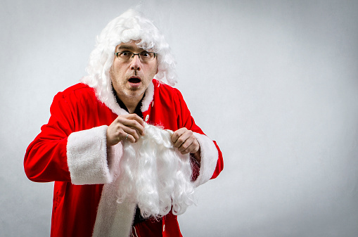 A man caught getting dressed as Santa Claus and making a surprised facial expression