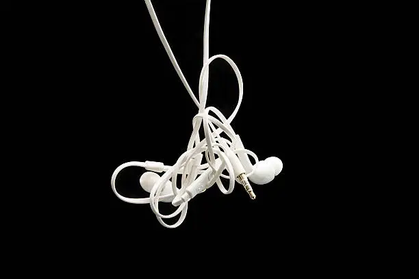 Tangled earbuds are amongst the most fustrating things in the world. these white earbuds are featured on a black background and are in sharp focus