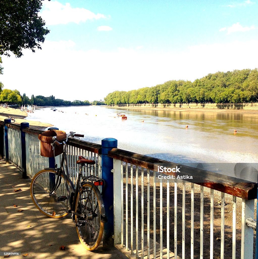 Bike and the River In summer day we see the bicycle left on the river bank, where in the background are rowing boats London - England Stock Photo