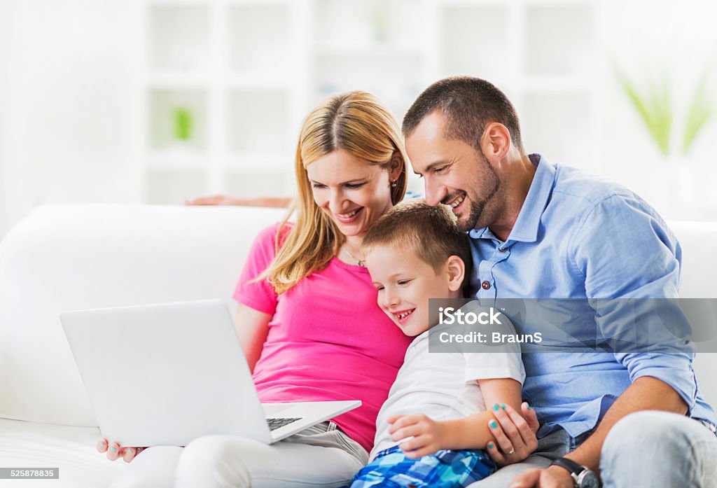 Family using laptop. Happy mid adult parents teaching their son how to use a computer. 30-39 Years Stock Photo