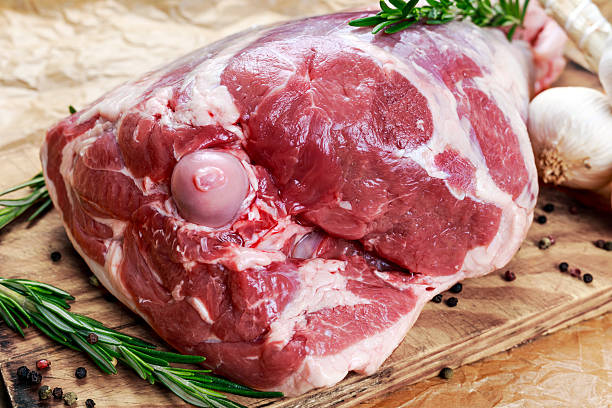 istock Raw lamb leg on crumpled paper background with herbs 525879134