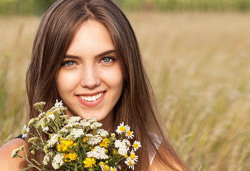 Portrait of young beautiful cute romantic  girl wearing a wreath of wild flowers in summer day, outdoors. Happy woman. Series of photos