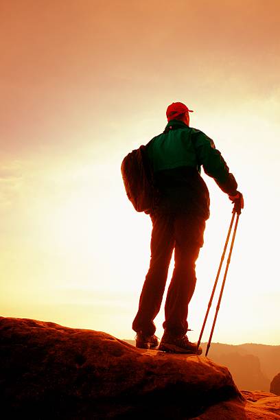 istock Tourist with sporty backpack on cliff and watching to Sun 525880920