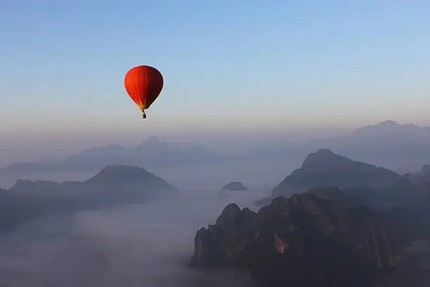 Photo of Red Hot-air Balloon float over Misty Mountain