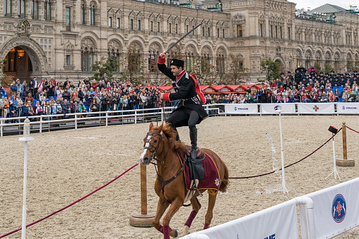 Moscow, Russia - September 7, 2015: Cossack of the Kremlin School of Horse Riding in full-dress uniform demonstrates skill of trick riding on International Military Music Festival 'Spasskaya Tower'. 