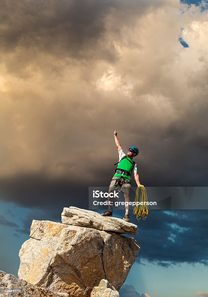 Conquer the mountain. Climber on the summit of a challenging cliff. Achievement Stock Photo