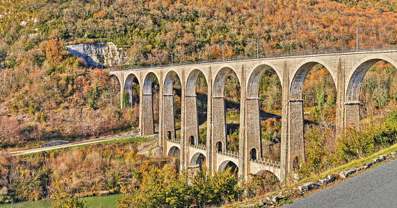 High definition of viaduct of Cize-Bolozon in autumn season in Bugey in Ain, Rhone-Alpes region in France. This viaduct is a combination rail and vehicular viaduct crossing the Ain river gorge connecting the communes of Cize and Bolozon. An original span built in the same location in 1875 was destroyed in World War II. Reconstructed as an urgent post-war project due to its position on a main line to Paris, the new viaduct reopened in May 1950. It carries road and rail traffic at different levels.