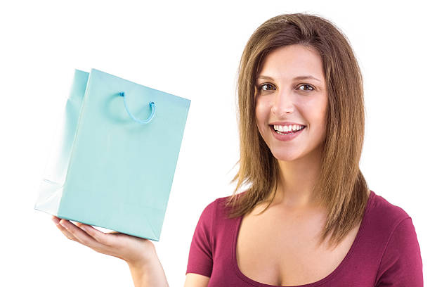 istock Brunette holding a gift bag smiling at camera 525900307