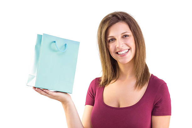 istock Brunette holding a gift bag smiling at camera 525900309