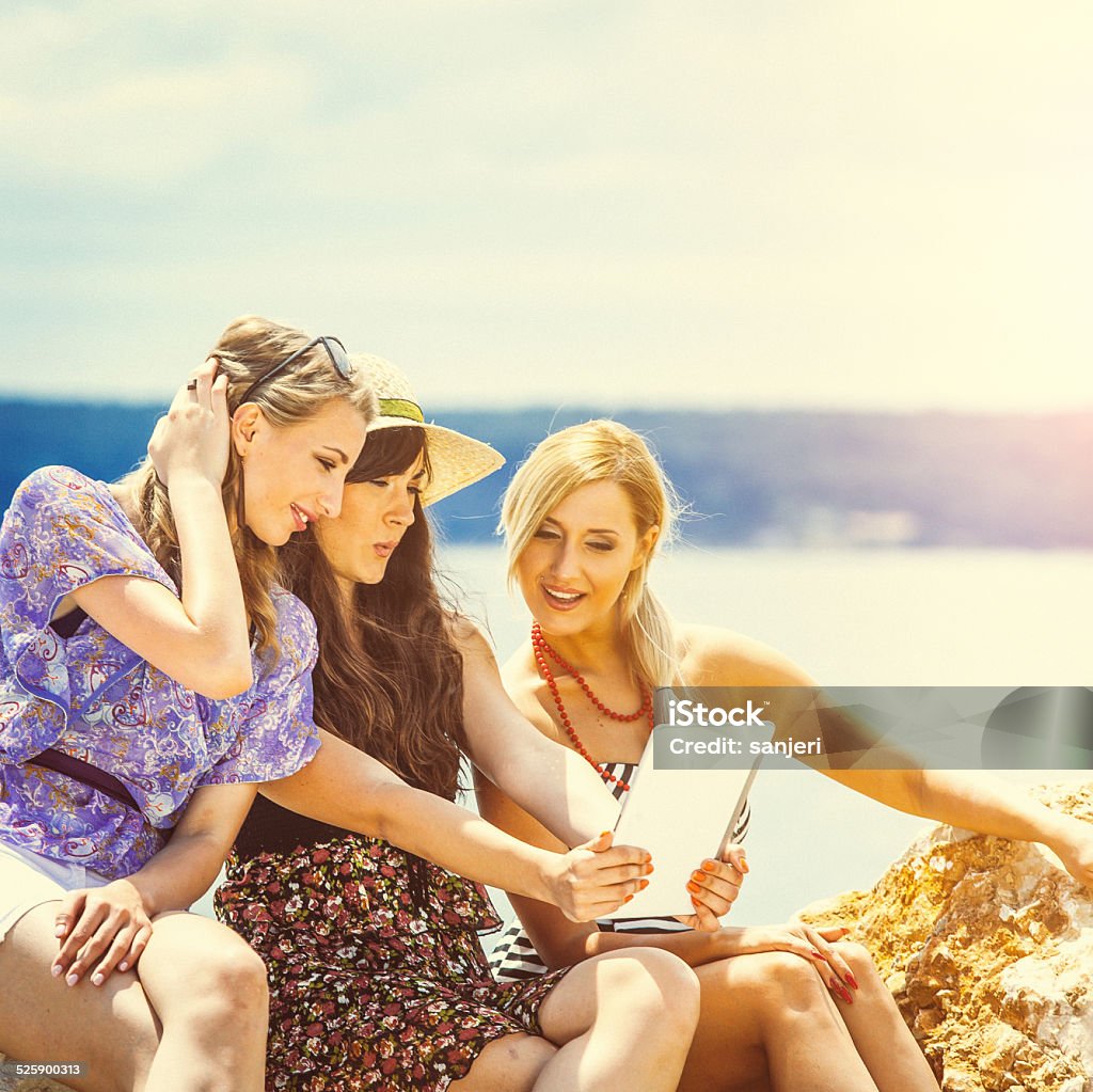 Teenage girls using digital tablet on the beach 20-24 Years Stock Photo