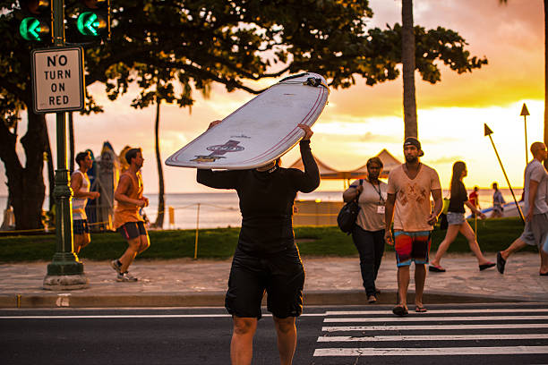 woman holding paddleboard crossing street, waikiki beach - editorial women paddleboard surfboard stock-fotos und bilder
