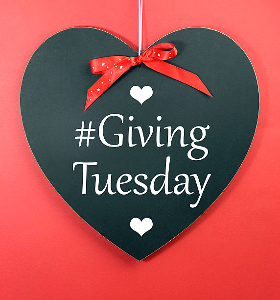 Giving Tuesday Giving Tuesday message greeting on black heart shape blackboard against a red background. giving tuesday stock pictures, royalty-free photos & images