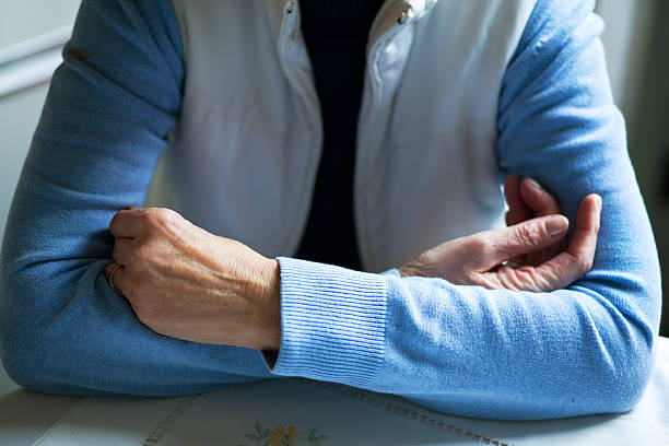 istock Crossed arms of senior on table 525939807