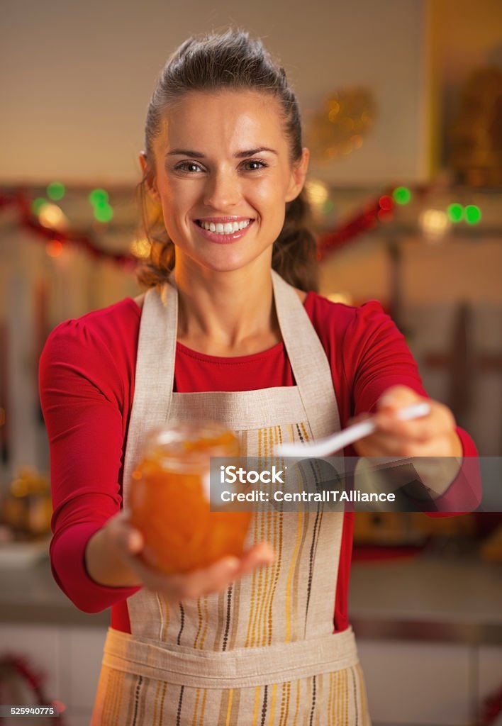happy young housewife giving spoon of orange jam Happy young housewife giving spoon of orange jam Women Stock Photo