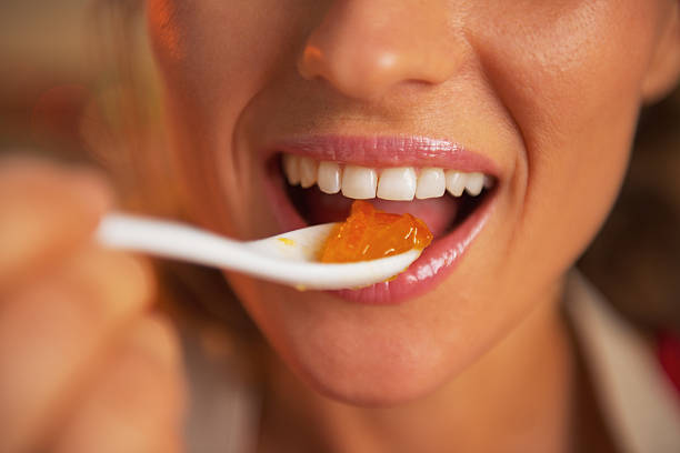 detalhe da mulher jovem feliz comendo geleia de laranja - gelatin dessert orange fruit marmalade - fotografias e filmes do acervo