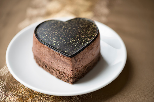 A luxurious chocolate mousse cake decorated with gold dust on a gold brocade tablecloth, from a Hong Kong bakery.  Hong Kong version of a French pastry.