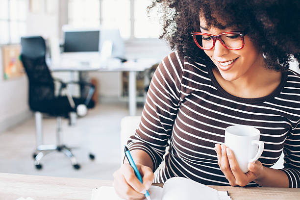 Cheerful female office worker sitting on desk