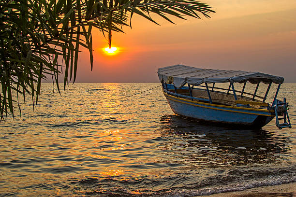 美しい眺めのボートに浮かぶ波の夕日に - lake victoria ストックフォトと画像