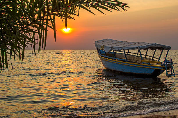 Idyllic view on boat floating on waves against of sunset Beautiful view on moored boat on waves against of sunset at sea. Lake Victoria, Tanzania lake victoria stock pictures, royalty-free photos & images