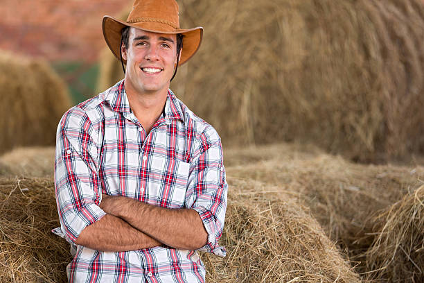 istock cowboy standing against hay bales 525956493