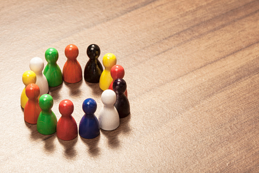 Diversity concept, friends in different colors,  colorful toy pawns. On wood table.