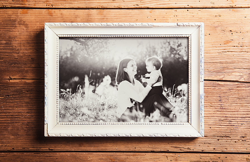 Mothers day composition. Photo of mother and son in picture frame. Studio shot on wooden background.