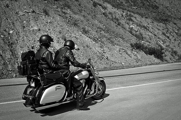 Big Sur, USA - April 16, 2014: Two middle aged bikers on the journey down the Big Sur Coastline on Highway 1 on their touring bike and clad in old style 50s leathers and helmets.