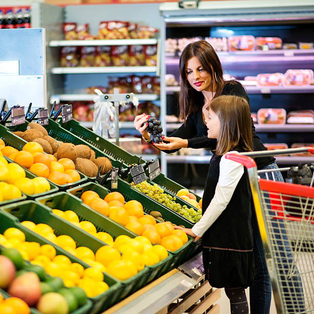 istock Mother and daughter buying fruit together 525965311