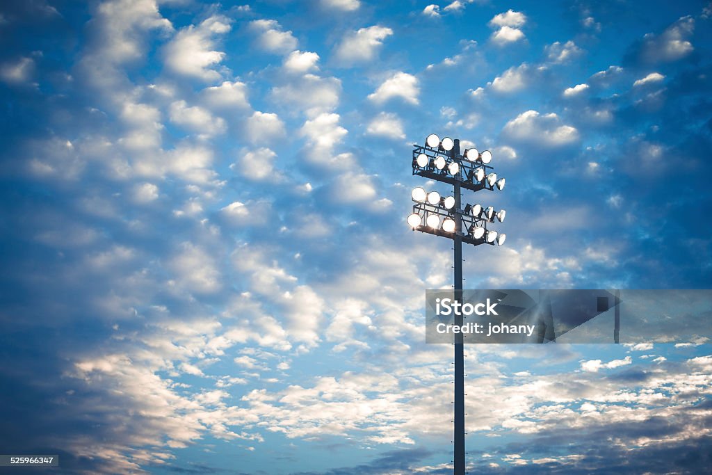 Football stadium lights The lights of a football stadium against a cloudy blue sky. Floodlight Stock Photo