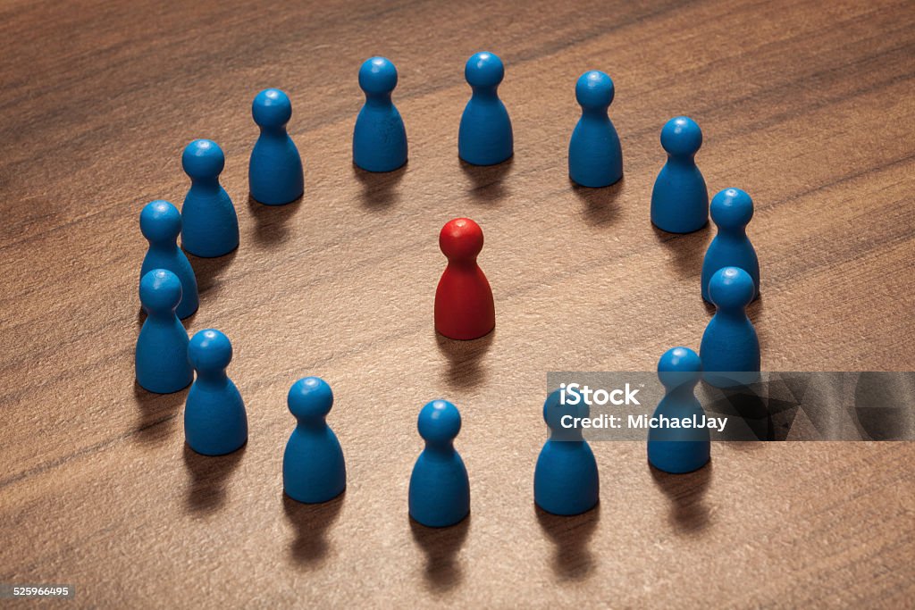 Inside the circle, figurine concept on wood table One within the circle of friends. Concept with toy pawn figurines on wood table. Blue Stock Photo