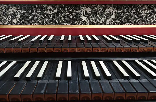 Old antique, historic, two rowed piano keyboard and beautiful ornaments on its forehead.