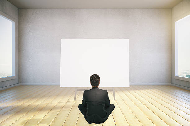 istock man sits on the floor and looking at blank poster 525970854