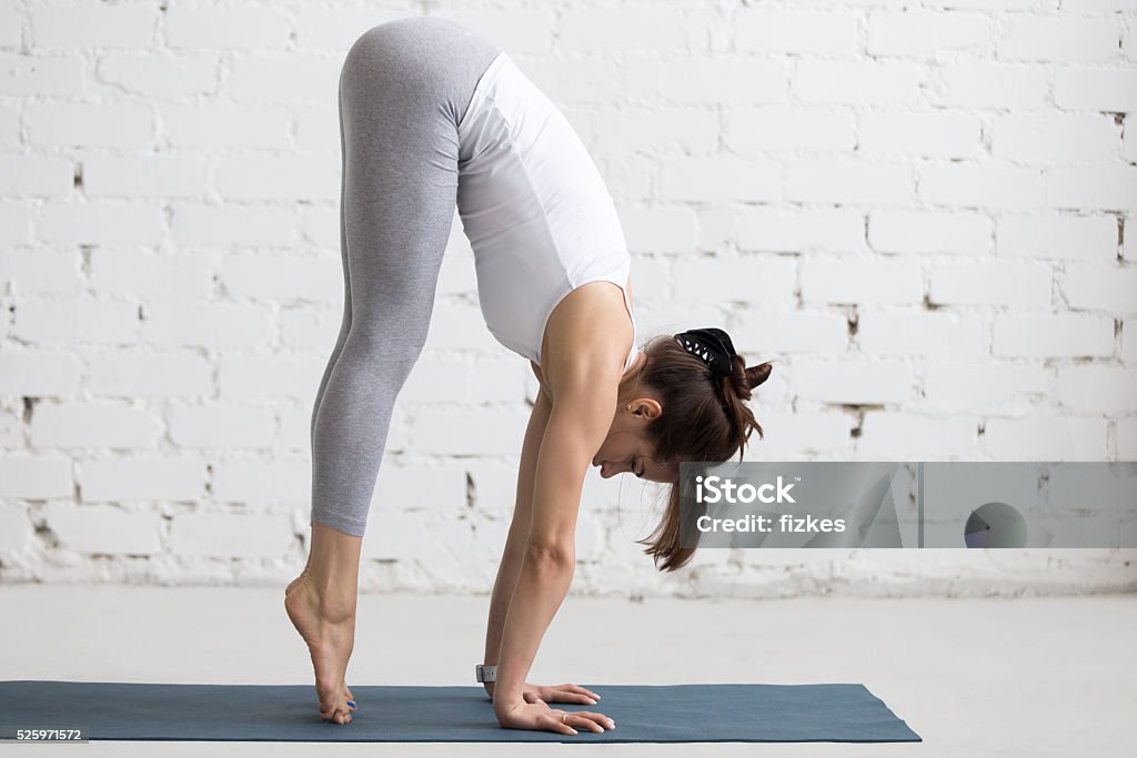 Yoga Indoors: preparation for Handstand pose Beautiful young woman working out in loft interior, doing yoga exercise on blue mat, preparation for handstand, side view, full length Activity Stock Photo