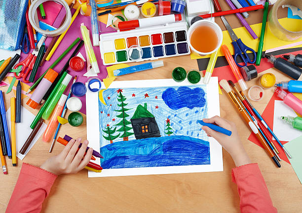 istock child drawing christmas night in forest with house 525975622
