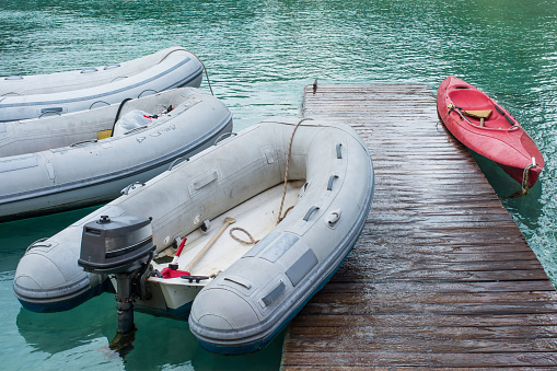 Three inflatable rafts and a red kayak docked at a marina.