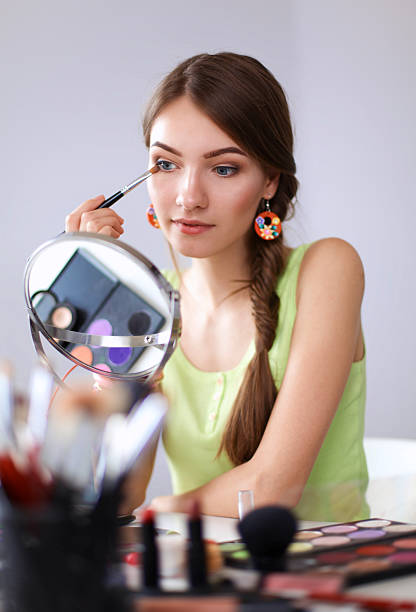 istock Young beautiful woman making make-up near mirror,sitting at 525984122
