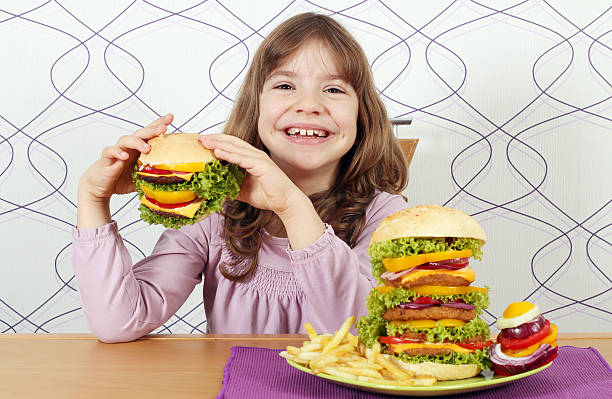 istock hungry little girl eat hamburger 525985493
