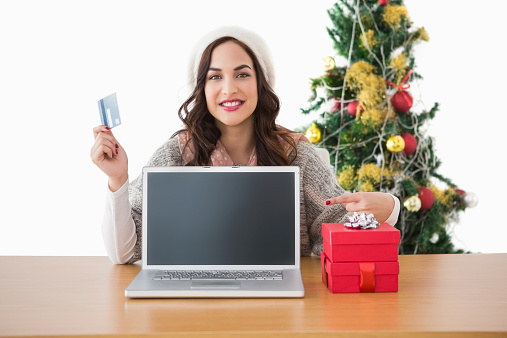 Brunette holding credit card and showing her laptop on white background