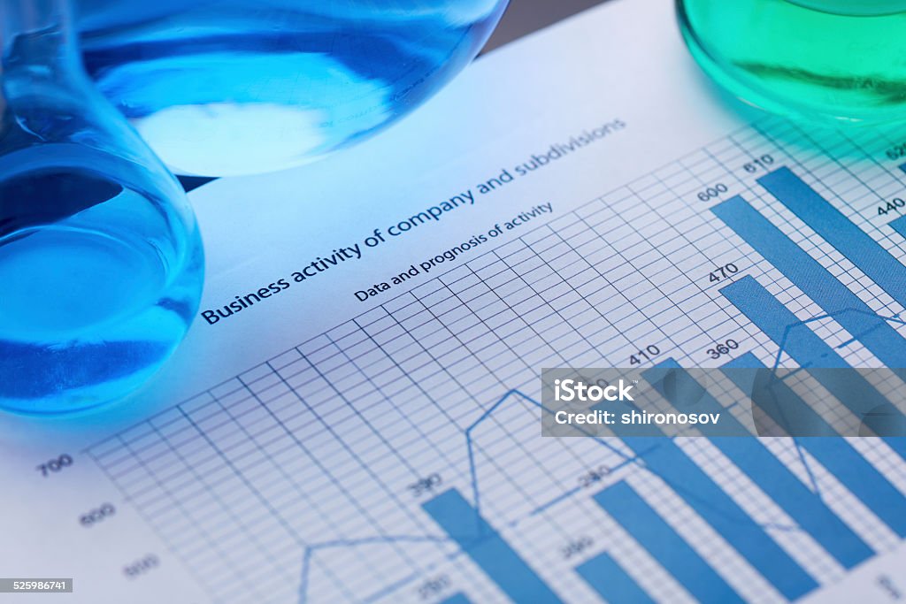 Glassware on document Test-tubes with blue and green liquids on document with financial data Beaker Stock Photo