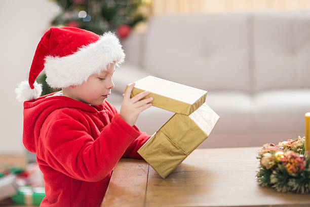 istock Festive little boy opening a gift 525987417