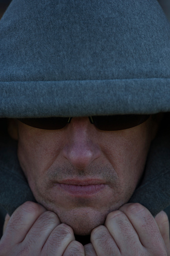 Man wearing hoodie and sunglasses with villainous appearance